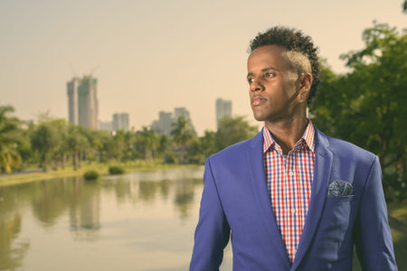 Young handsome African businessman relaxing at the park in Bangkok, Thailand