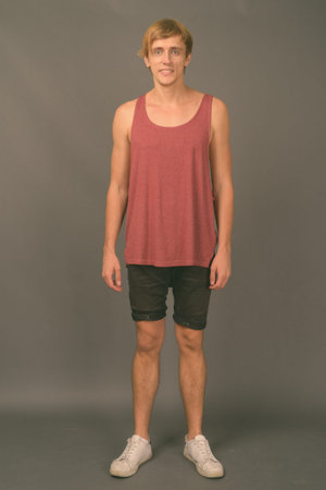 Young handsome man ready for gym against gray background
