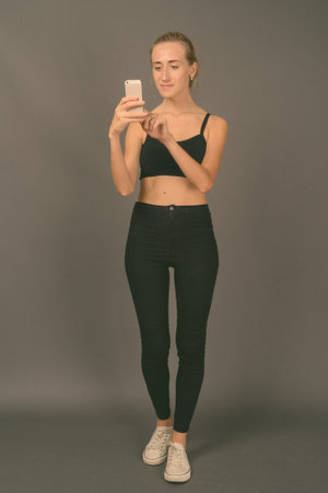 Young beautiful woman ready for gym against gray backgroundの写真素材