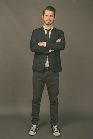 Young handsome bearded businessman against gray backgroundの写真素材