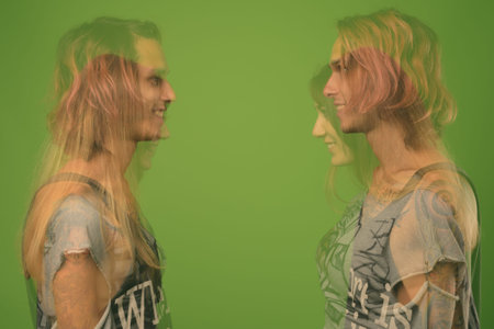 Studio shot of young rebellious man and woman together against green background