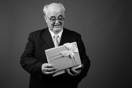 Overweight senior businessman wearing eyeglasses against brown background