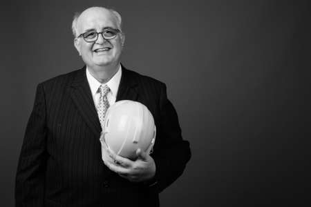 Overweight senior businessman with hardhat against brown backgroundの写真素材