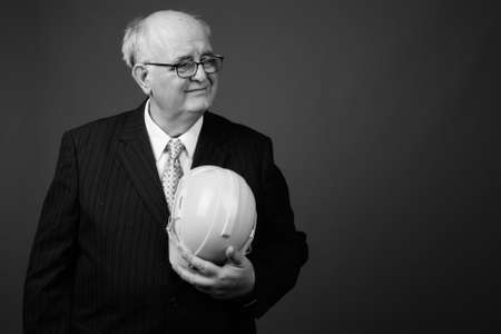 Overweight senior businessman with hardhat against brown backgroundの写真素材
