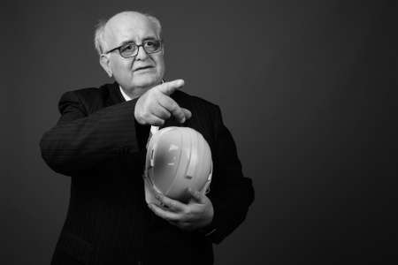 Overweight senior businessman with hardhat against brown backgroundの写真素材