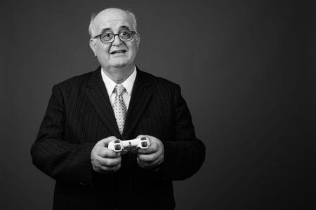 Overweight senior businessman wearing eyeglasses against brown backgroundの写真素材