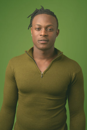Young handsome African man from Kenya against green background