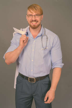 Bearded man doctor with blond hair against gray backgroundの写真素材