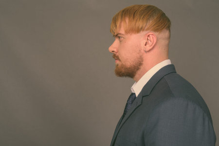 Bearded businessman with blond hair against gray background