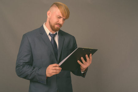 Bearded businessman with blond hair against gray background