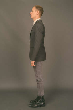 Portrait of young handsome businessman against gray backgroundの写真素材
