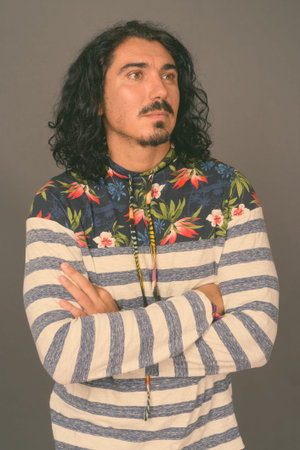 Handsome man with curly hair and mustache against gray background