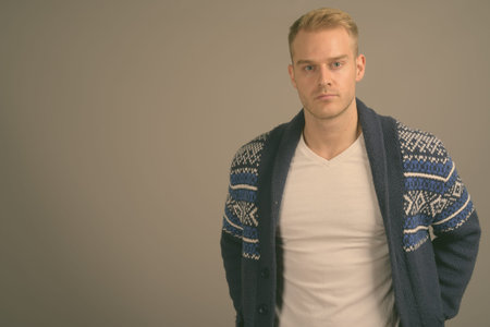 Young handsome man with blond hair against gray background