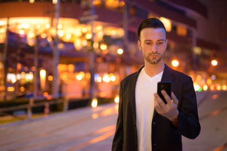 Portrait of young businessman against a city by nightの写真素材