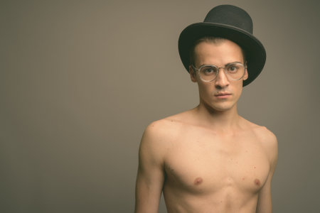 Young handsome man shirtless against gray backgroundの写真素材