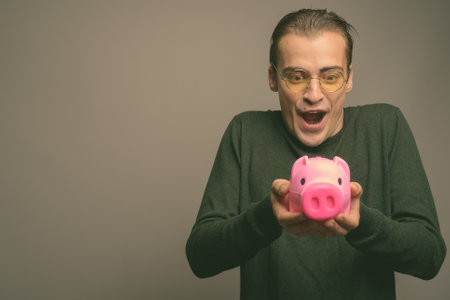 Young handsome man wearing green long sleeved shirt against gray backgroundの写真素材