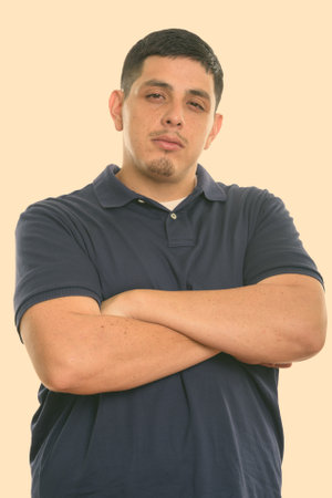 Studio shot of young Hispanic man with arms crossedの写真素材