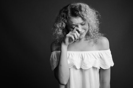 Young beautiful woman with blond curly hair against gray backgroundの写真素材