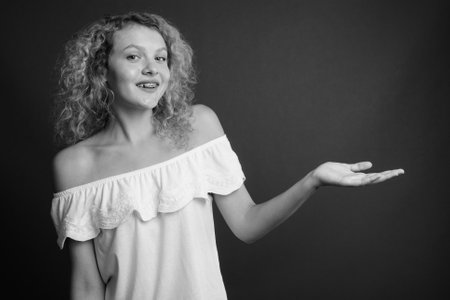 Young beautiful woman with blond curly hair against gray backgroundの写真素材