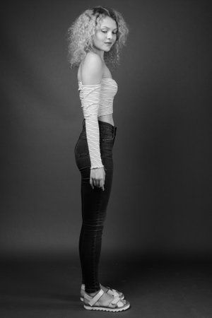 Young beautiful woman with blond curly hair against gray backgroundの写真素材