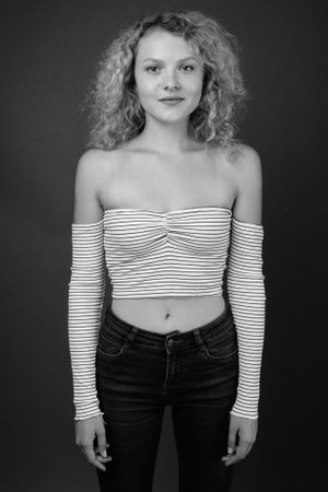 Young beautiful woman with blond curly hair against gray backgroundの写真素材