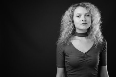 Young beautiful woman with blond curly hair against gray backgroundの写真素材