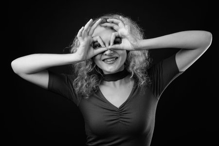 Young beautiful woman with blond curly hair against gray background