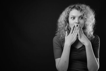 Young beautiful woman with blond curly hair against gray background