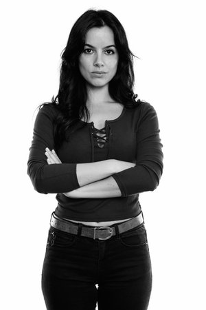 Studio shot of young beautiful Spanish woman standing with arms crossed