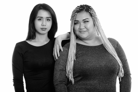 Young Asian transgender woman resting hand on fat Asian womanの写真素材