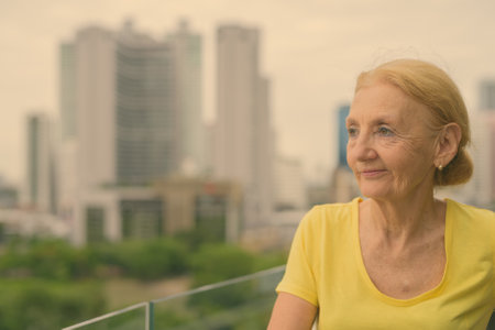 Beautiful senior woman with blond hair against view of the cityの写真素材