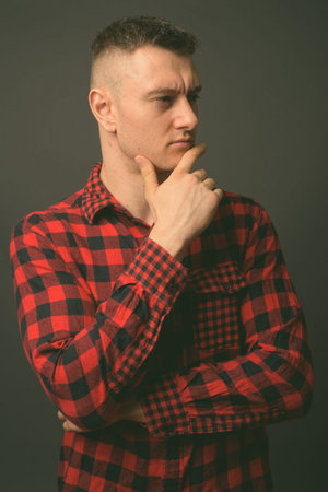 Studio shot of young handsome man against gray backgroundの写真素材