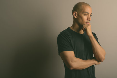 Handsome bald man wearing black shirt against gray backgroundの写真素材