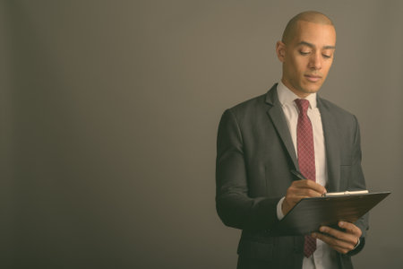Handsome bald businessman wearing suit against gray backgroundの写真素材