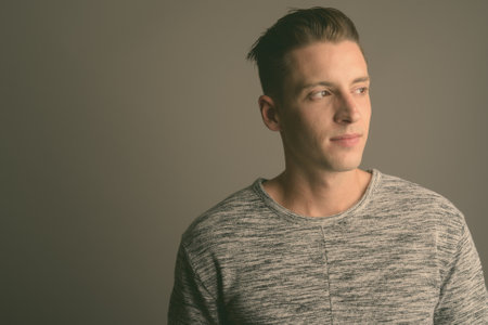 Young handsome man wearing gray shirt against gray backgroundの写真素材