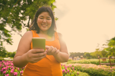 Beautiful overweight Asian woman relaxing at the park in the city of Bangkok, Thailand