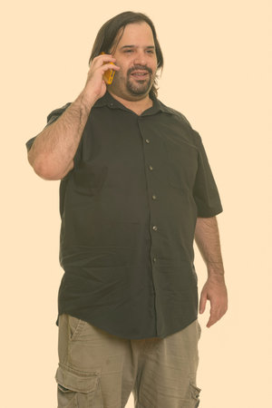 Happy fat Caucasian man smiling and talking on mobile phone