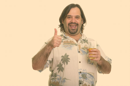 Happy fat Caucasian man smiling while giving thumb up and holding glass of beer ready for vacation