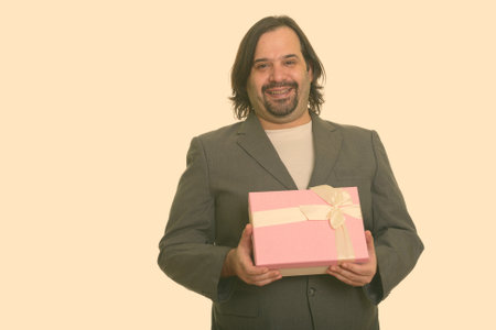 Happy fat Caucasian businessman smiling and holding gift boxの写真素材