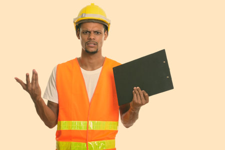 Young angry African man construction worker holding clipboard with both arms raisedの写真素材