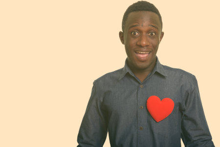Young happy African man smiling with red heart on chestの写真素材
