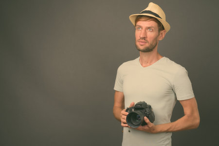 Studio shot of blond bearded tourist man against gray backgroundの写真素材