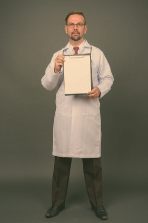 Blond bearded man doctor with goatee against gray background