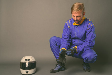 Blond bearded man motorcyclist with goatee in full gear against gray backgroundの写真素材