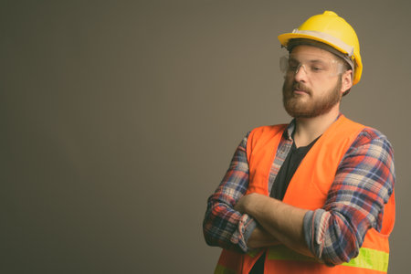 Young bearded man construction worker against gray backgroundの写真素材