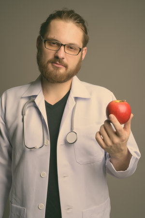 Young bearded man doctor against gray backgroundの写真素材