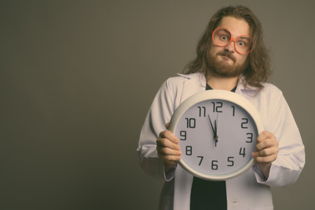 Young bearded man doctor against gray backgroundの写真素材