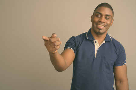 Young handsome African man wearing blue polo shirt against gray backgroundの写真素材