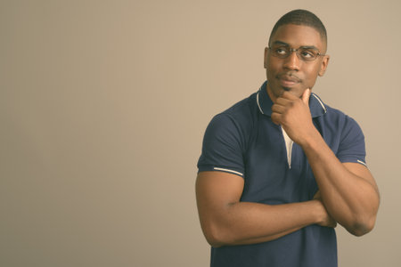 Young handsome African man wearing blue polo shirt against gray backgroundの写真素材