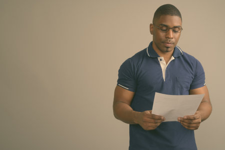 Young handsome African man wearing blue polo shirt against gray backgroundの写真素材